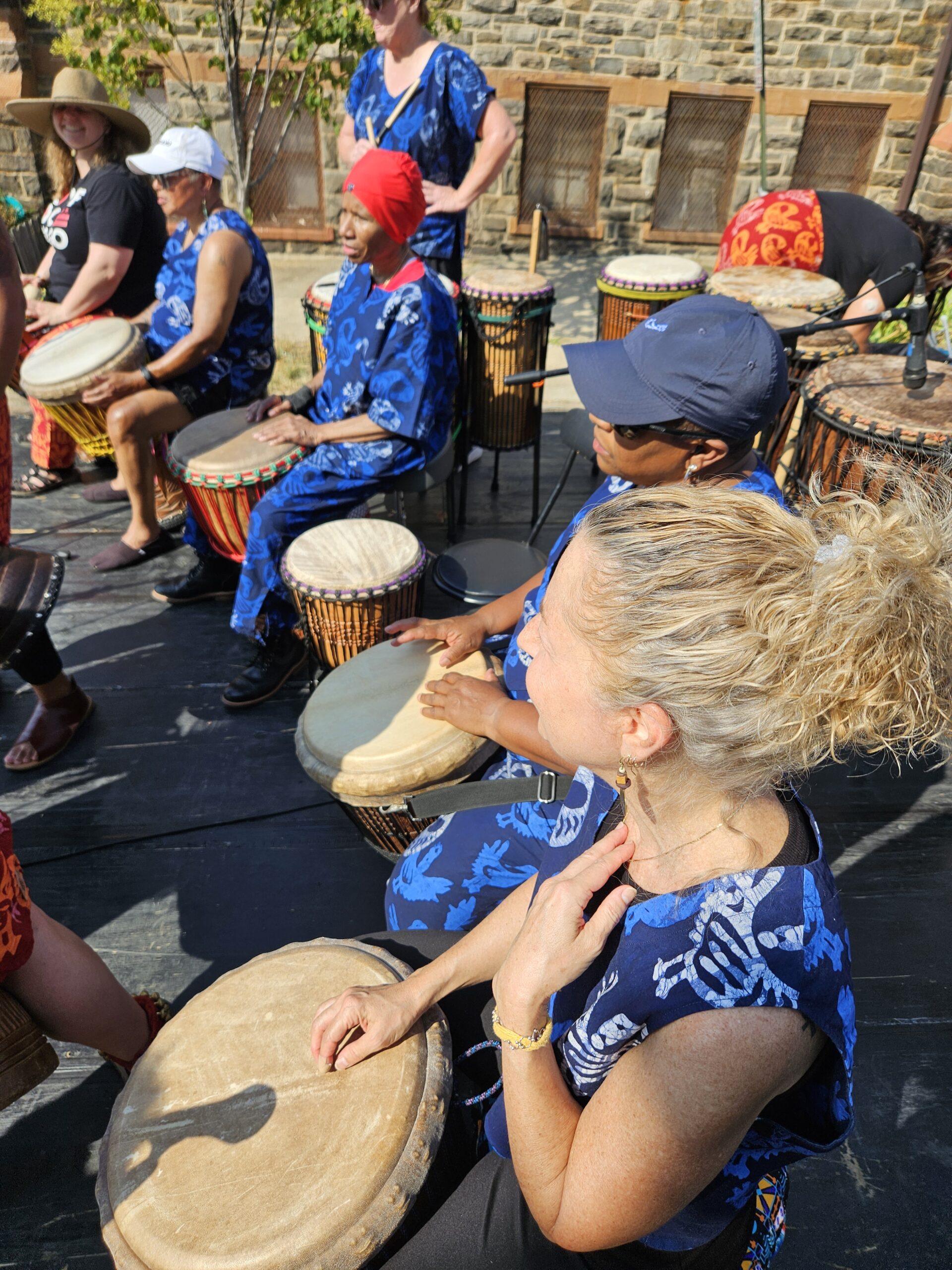 several Bele Bele members seated in a row with their drums