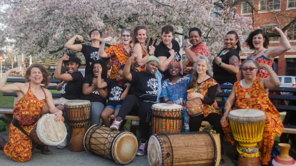 Bele Bele Rhythm Collective members pose for a group photo, flexing biceps